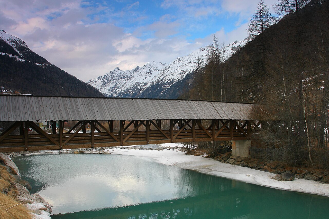 Gedeckte Holzbrücke über die Ötztaler Ache in Sölden vor verschneiten Bergen
